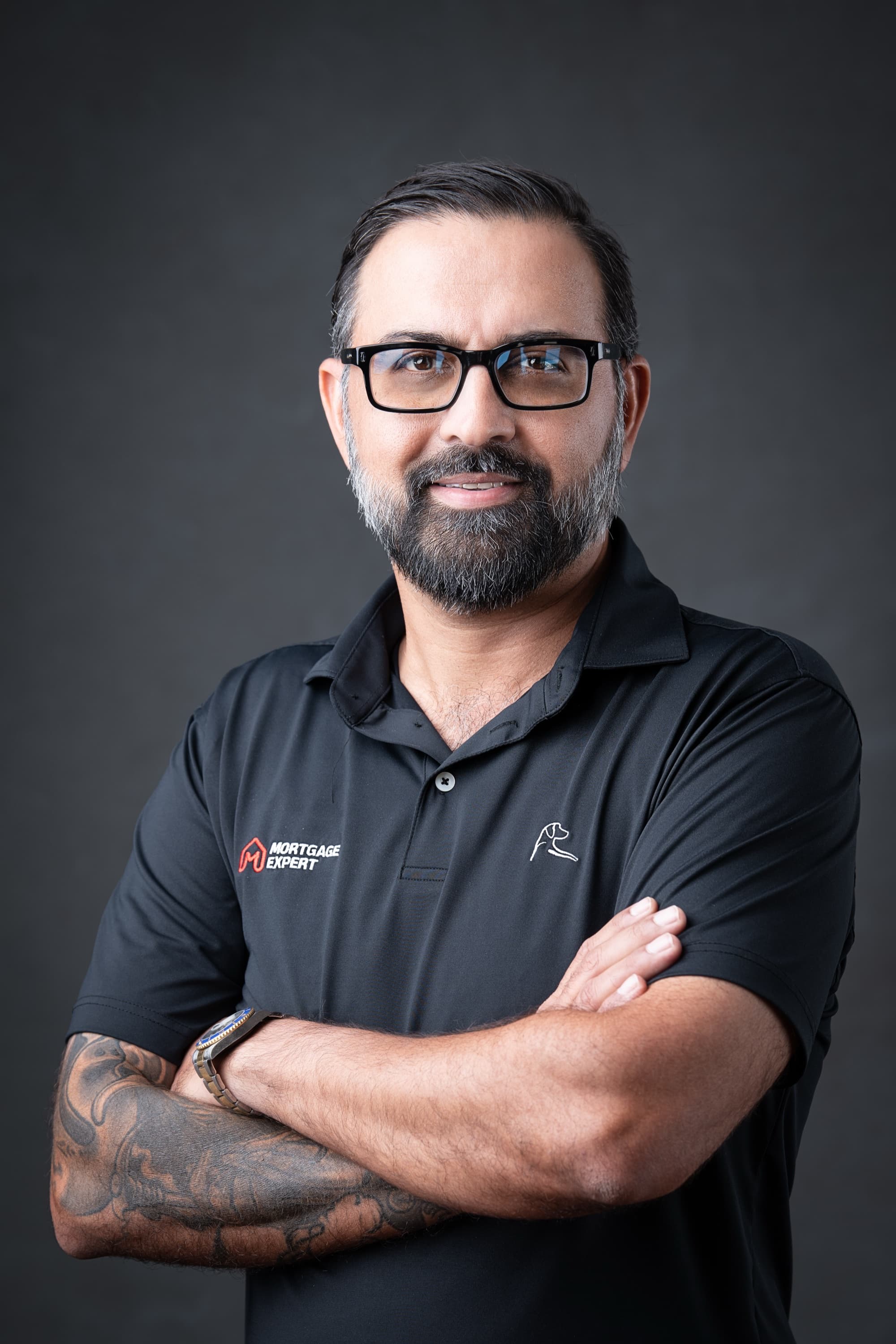 Shahram Sondi, Florida mortgage broker-owner, arms crossed in a Mortgage Expert polo against a charcoal studio backdrop