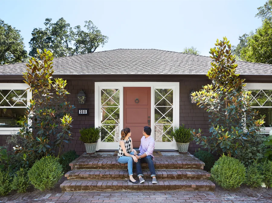 A couple sitting together on the front steps of the home they just bought